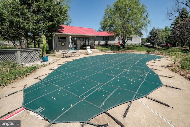 view of swimming pool with an outdoor structure, a patio area, fence, and a covered pool