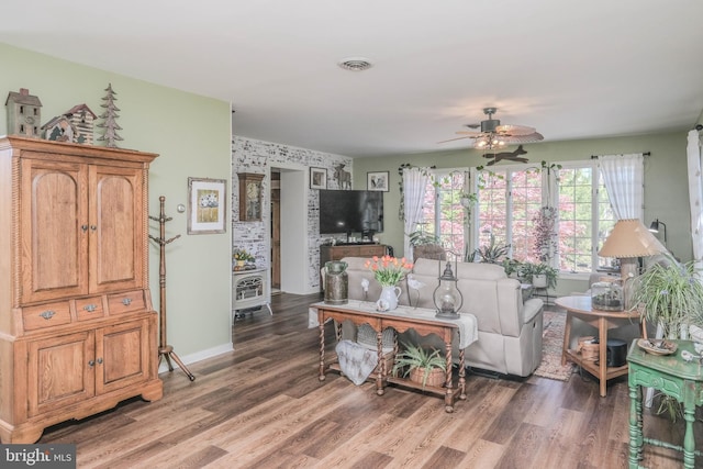 living room with baseboards, a ceiling fan, wood finished floors, and visible vents