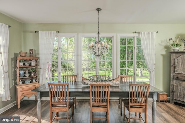dining area with baseboards, wood finished floors, and a notable chandelier