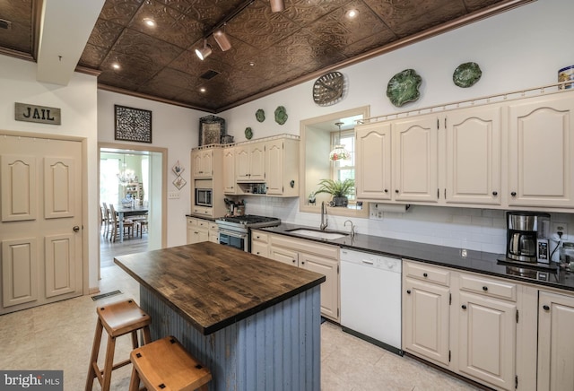 kitchen with ornamental molding, butcher block countertops, tasteful backsplash, a sink, and appliances with stainless steel finishes