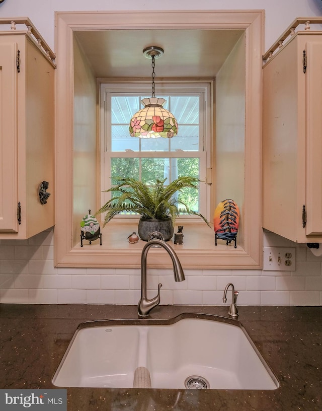 interior details featuring decorative light fixtures, decorative backsplash, a sink, and dark stone countertops