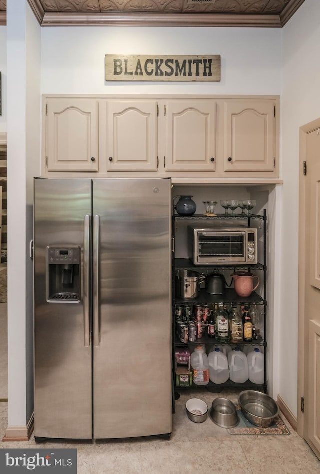 kitchen featuring cream cabinets, stainless steel refrigerator with ice dispenser, and baseboards