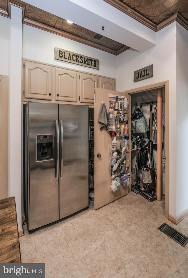 kitchen with stainless steel refrigerator with ice dispenser, freestanding refrigerator, crown molding, and visible vents