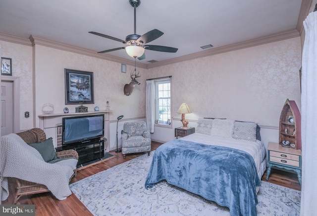 bedroom featuring ceiling fan, visible vents, ornamental molding, and wood finished floors