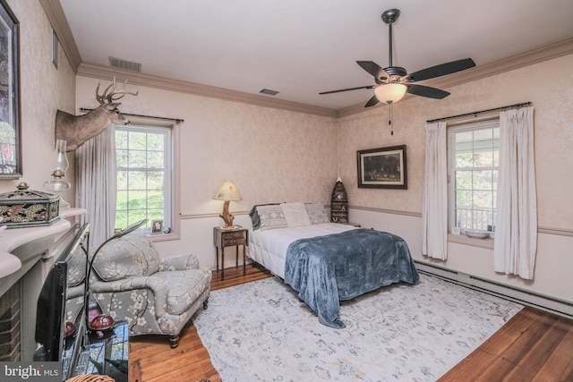 bedroom with crown molding, visible vents, a baseboard radiator, and hardwood / wood-style floors
