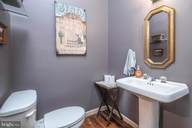 half bathroom featuring toilet, baseboards, and wood finished floors