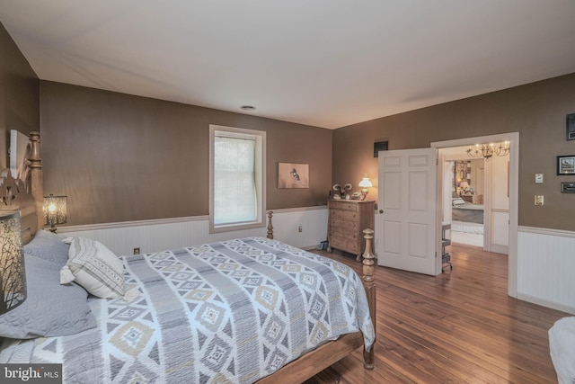 bedroom with an inviting chandelier, wainscoting, and hardwood / wood-style floors