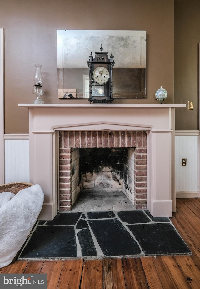 details with a wainscoted wall, a brick fireplace, and wood finished floors