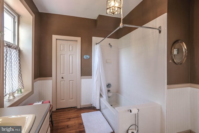 full bathroom with a wainscoted wall, shower / bath combination with curtain, hardwood / wood-style floors, and a chandelier