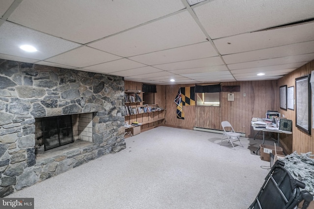 interior space with a drop ceiling, wooden walls, and a fireplace