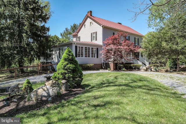 view of front of property with a chimney, metal roof, and a front lawn