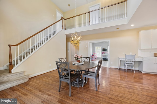 dining space featuring a notable chandelier, light wood-style floors, stairs, recessed lighting, and a towering ceiling