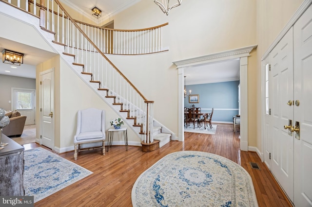 entryway with ornamental molding, a high ceiling, a chandelier, and stairway