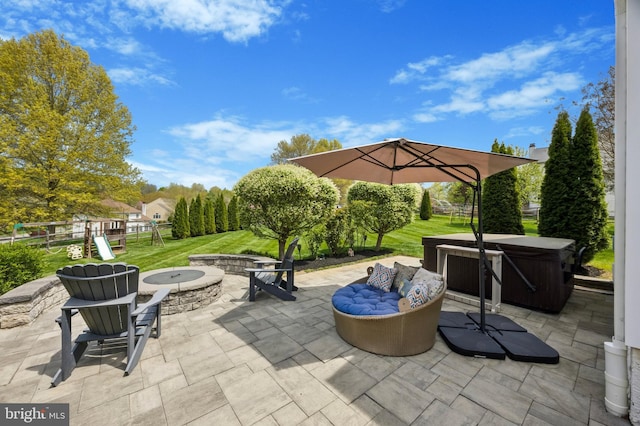 view of patio / terrace featuring a hot tub, fence, a fire pit, and a playground