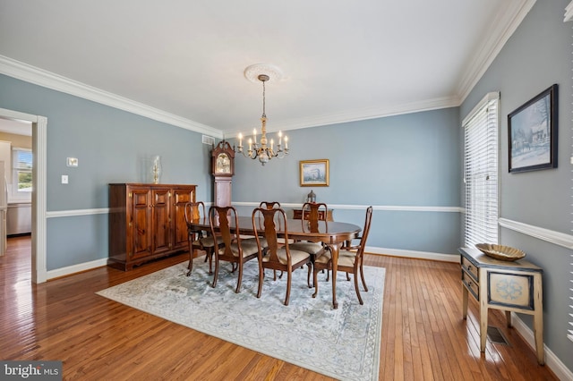 dining area with crown molding, baseboards, a chandelier, and wood-type flooring