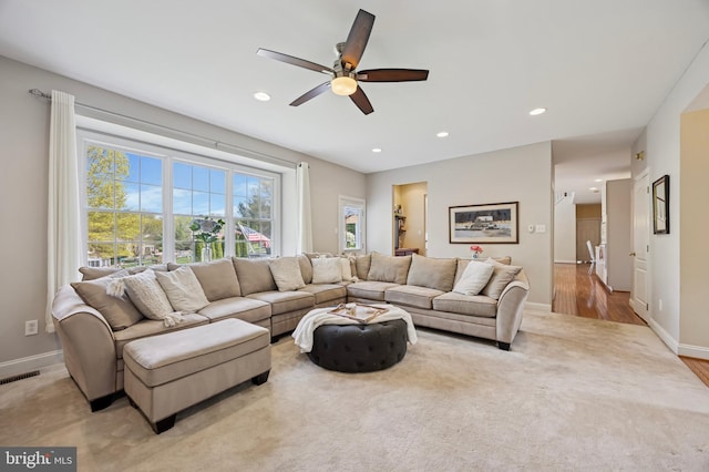 carpeted living area with baseboards, plenty of natural light, a ceiling fan, and visible vents