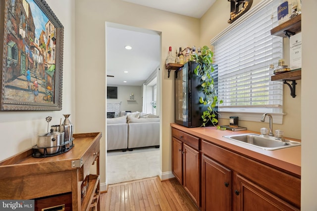 kitchen with brown cabinets, a sink, light countertops, recessed lighting, and light wood-style flooring