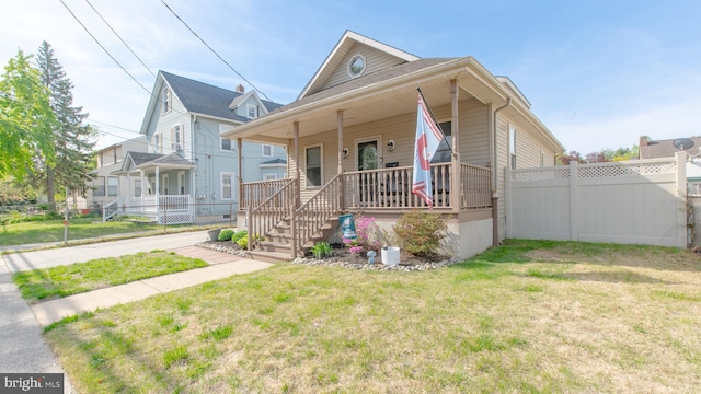 view of front of home with a front lawn, fence, and covered porch