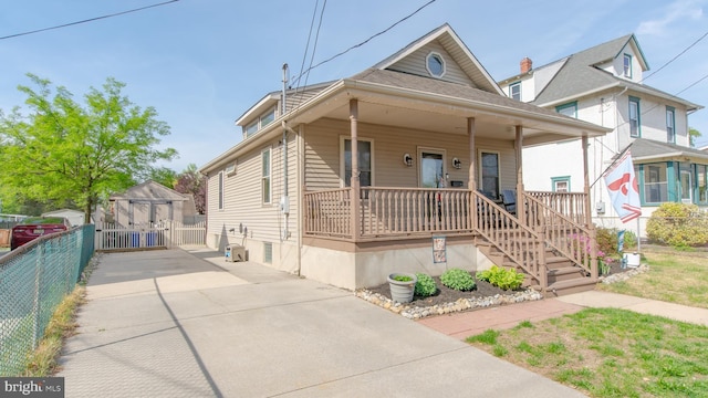 view of front of home with fence, a shed, an outbuilding, concrete driveway, and covered porch
