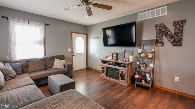 living area featuring visible vents, wood finished floors, baseboards, a textured ceiling, and a ceiling fan