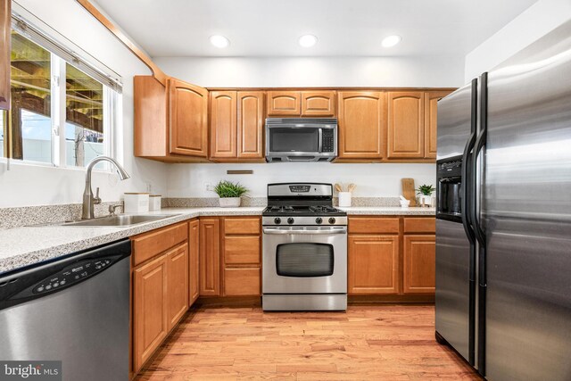kitchen featuring recessed lighting, light countertops, a sink, light wood finished floors, and stainless steel appliances