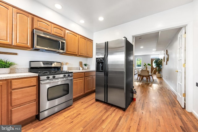 kitchen featuring brown cabinets, light wood-type flooring, light countertops, stainless steel appliances, and recessed lighting