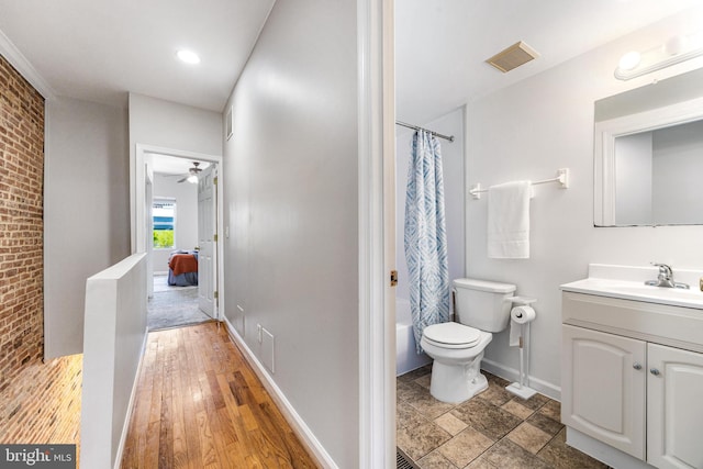full bathroom featuring a ceiling fan, toilet, visible vents, and brick wall