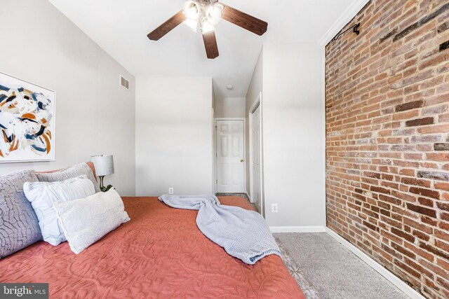 carpeted bedroom featuring visible vents, baseboards, ceiling fan, and brick wall