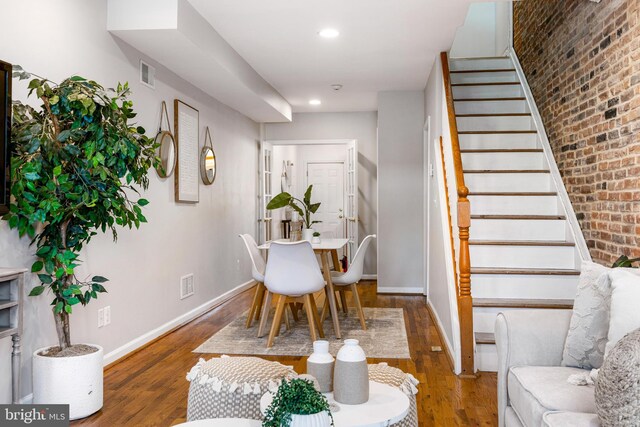 dining space featuring visible vents, stairs, wood finished floors, brick wall, and baseboards