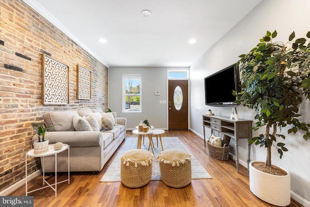 living room featuring brick wall, baseboards, and wood finished floors