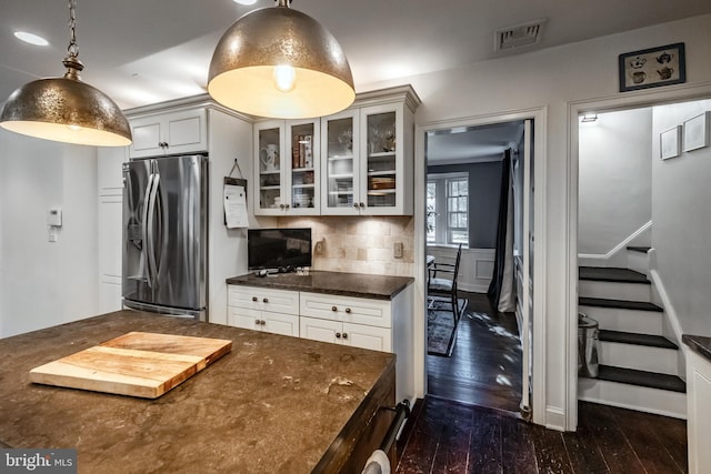 kitchen featuring dark wood-style flooring, stainless steel fridge, decorative backsplash, visible vents, and glass insert cabinets