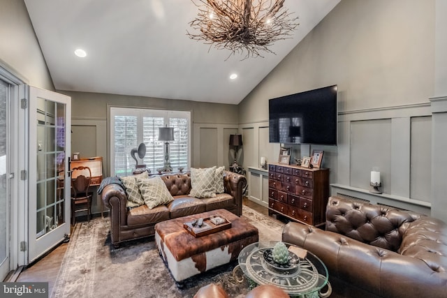 living area with high vaulted ceiling, a decorative wall, recessed lighting, and a notable chandelier