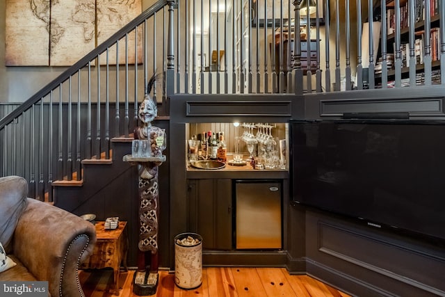 bar featuring wood-type flooring, stairs, and a bar