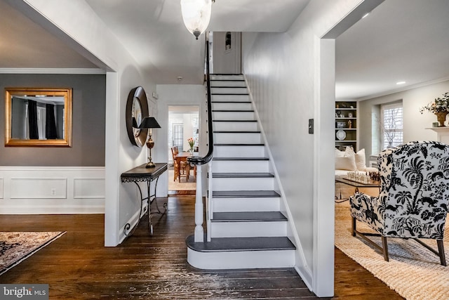 staircase with built in shelves, ornamental molding, and hardwood / wood-style floors