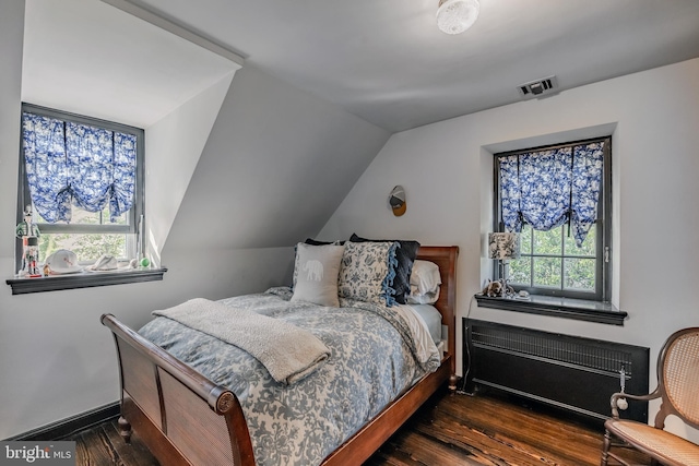 bedroom with wood finished floors, radiator heating unit, visible vents, and multiple windows
