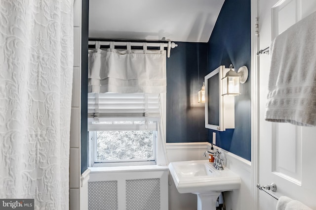 bathroom featuring a decorative wall, a sink, and a wainscoted wall
