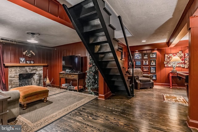 living area with wooden walls, stairs, a textured ceiling, and wood finished floors
