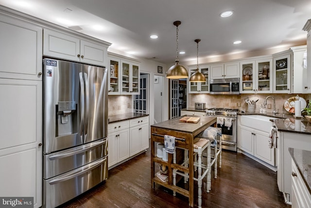 kitchen featuring dark wood-style flooring, appliances with stainless steel finishes, tasteful backsplash, a sink, and recessed lighting