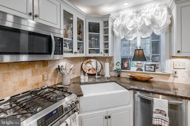 kitchen featuring a sink, glass insert cabinets, tasteful backsplash, and stainless steel appliances