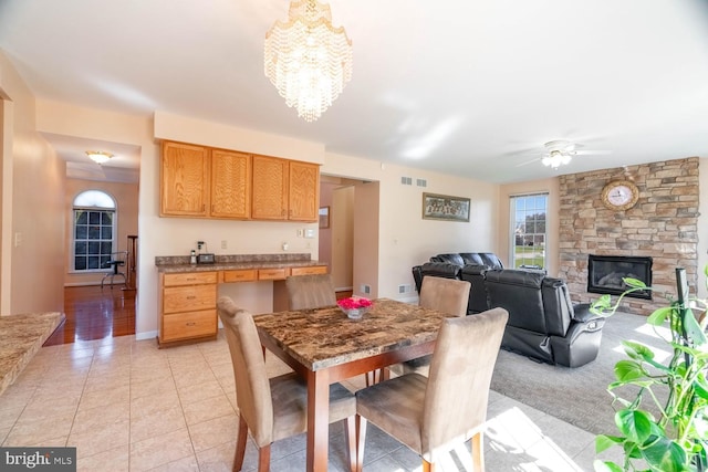 1249 Canon Way, Westminster, MD 21157 - dining room with a stone fireplace, visible vents, light tile patterned floors, baseboards, and ceiling fan with notable chandelier