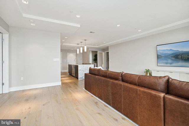 living room featuring visible vents, a raised ceiling, baseboards, light wood finished floors, and recessed lighting