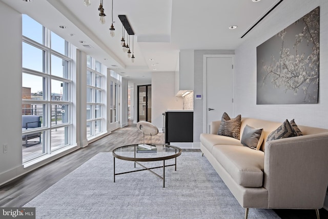 living room with a tray ceiling, recessed lighting, and wood finished floors