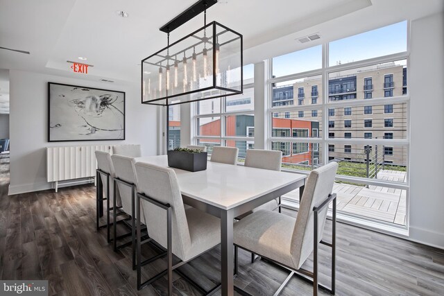 dining space featuring visible vents, a raised ceiling, baseboards, dark wood-style floors, and a chandelier