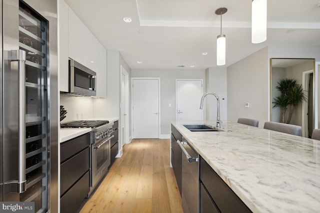 kitchen featuring dark brown cabinetry, modern cabinets, a sink, stainless steel appliances, and light wood-style flooring
