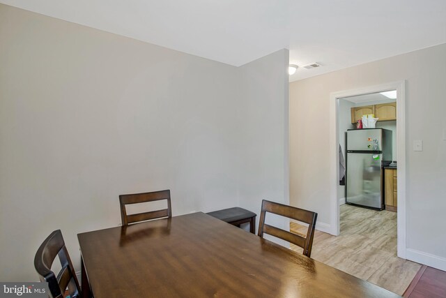 unfurnished dining area with baseboards, light wood finished floors, and visible vents