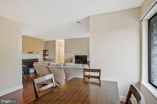 dining room featuring baseboards, wood finished floors, visible vents, and a fireplace
