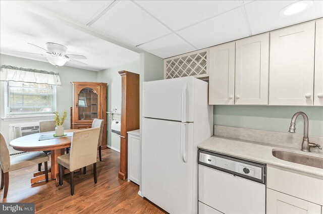 kitchen with wood finished floors, white appliances, light countertops, white cabinets, and a sink
