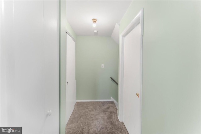 hallway with baseboards, carpet, and an upstairs landing