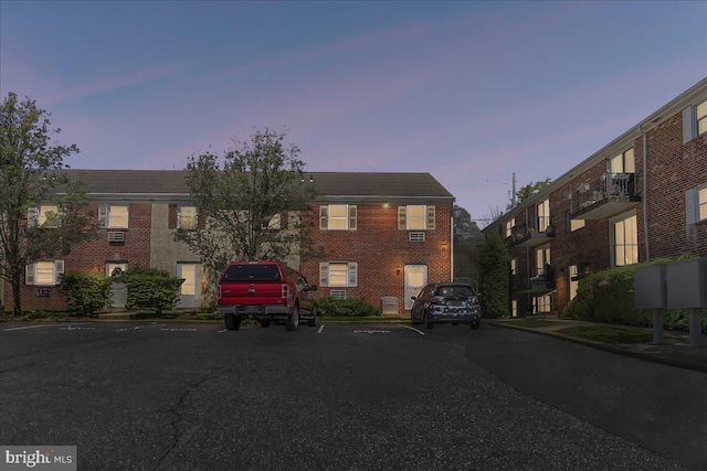 view of property with brick siding and uncovered parking