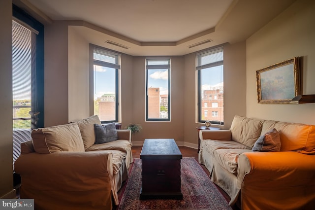 living area featuring visible vents, a raised ceiling, and baseboards